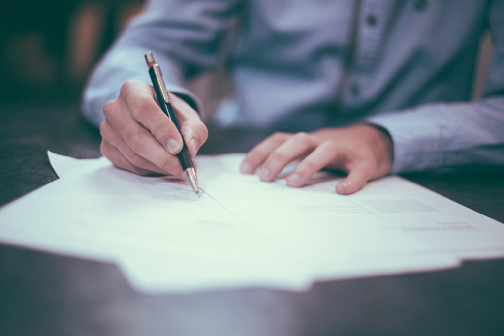 Photo of papers on desk with person writing on them
