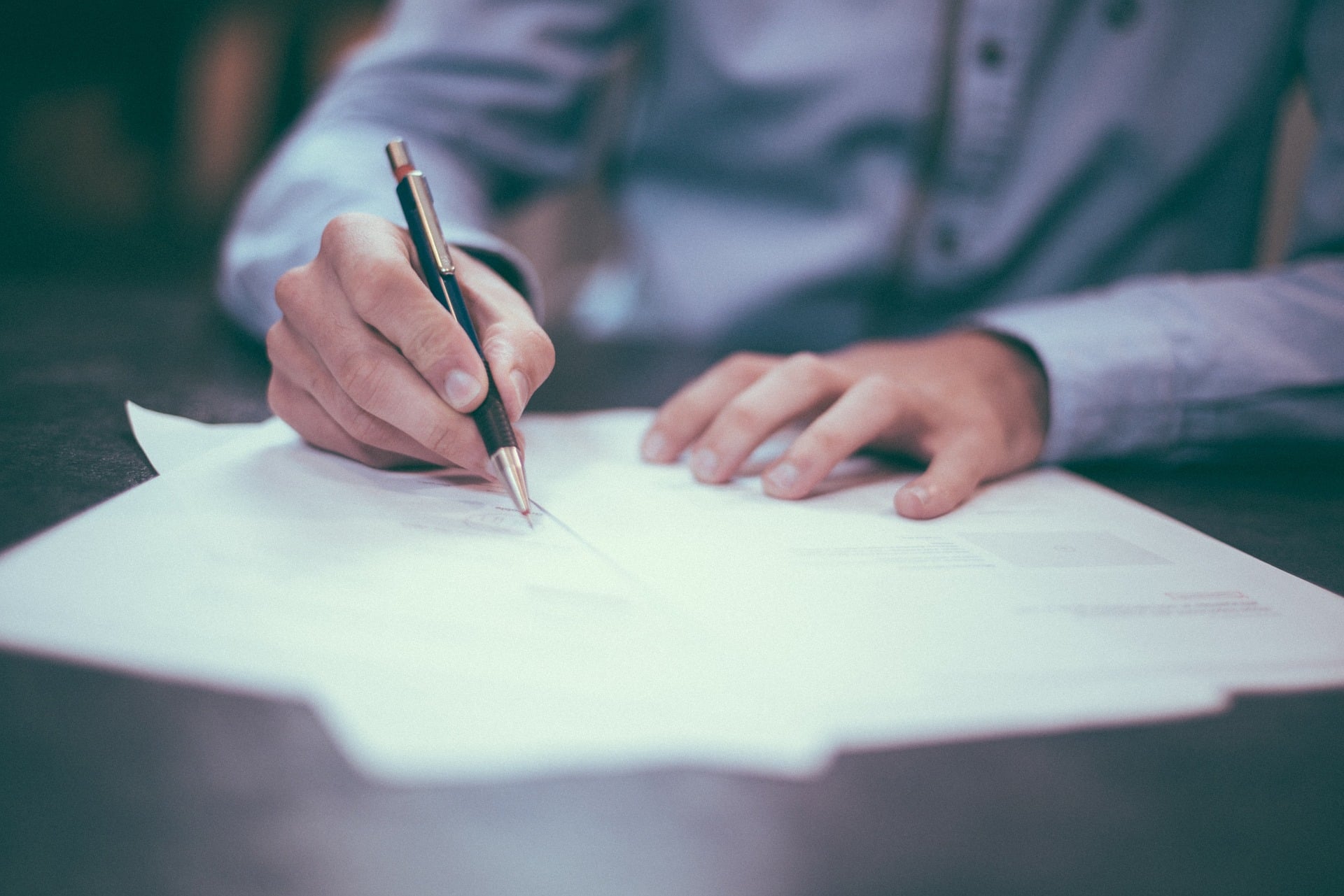 Photo of papers on desk with person writing on them