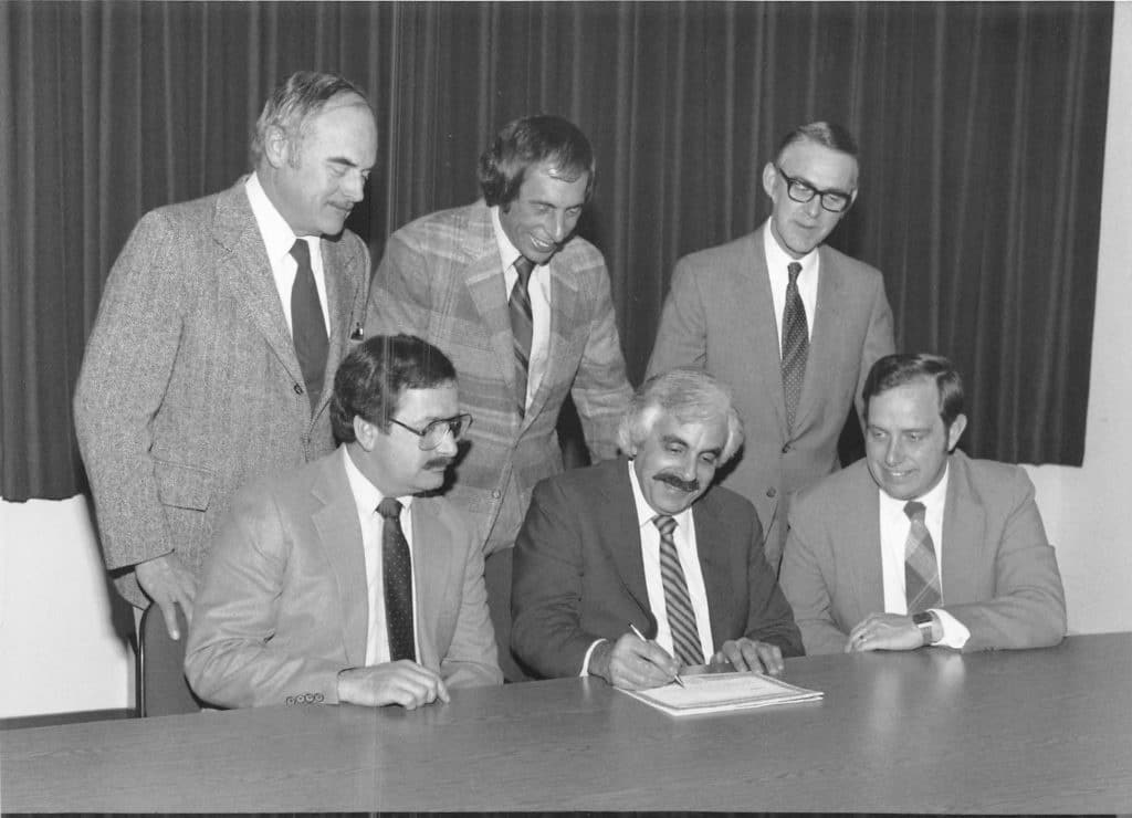 Hoyle, Tanner founders gathering around a document signing