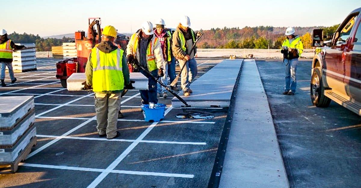 Construction photo with people painting lines and working on runway wearing safety vests
